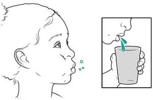 Child rinsing mouth and spitting into cup.