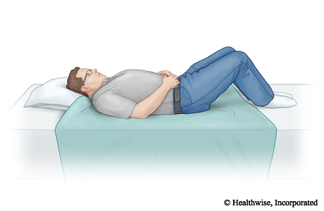 Una sábana doblada por la mitad y colocada en la cama en el lugar entre el que estarán las rodillas y la cabeza de la persona