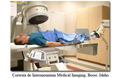 Una persona recostada debajo de una máquina de rayos X en un laboratorio de cateterismo cardíaco