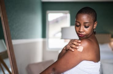 Person wearing birth control patch on upper arm.