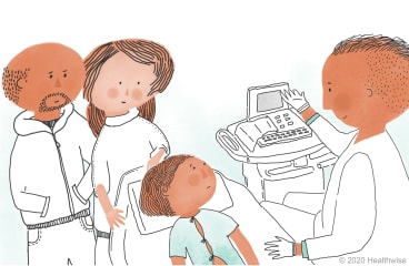 Elsie lies on the bed in her special shirt while Jeff shows her the computer