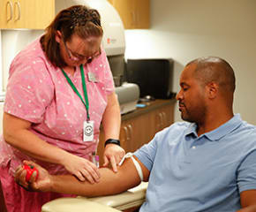 Proveedor de atención médica que extrae sangre del brazo de un hombre.