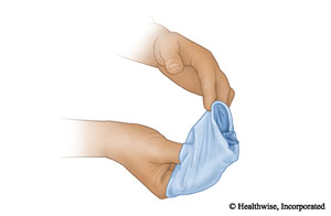 Quítese el segundo guante sacándoselo por encima del guante que está hecho una bola