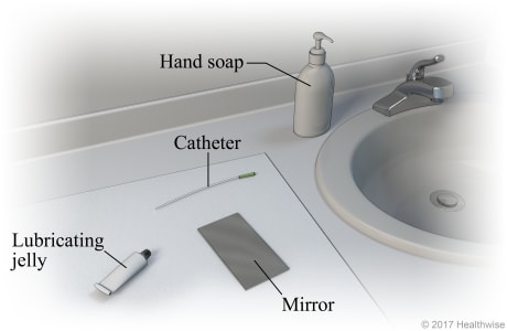 Bathroom sink area, showing supplies of hand soap, catheter, lubricating jelly, and mirror on clean cloth.