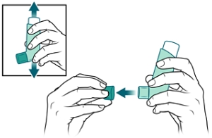 Person shaking inhaler and removing its cap.